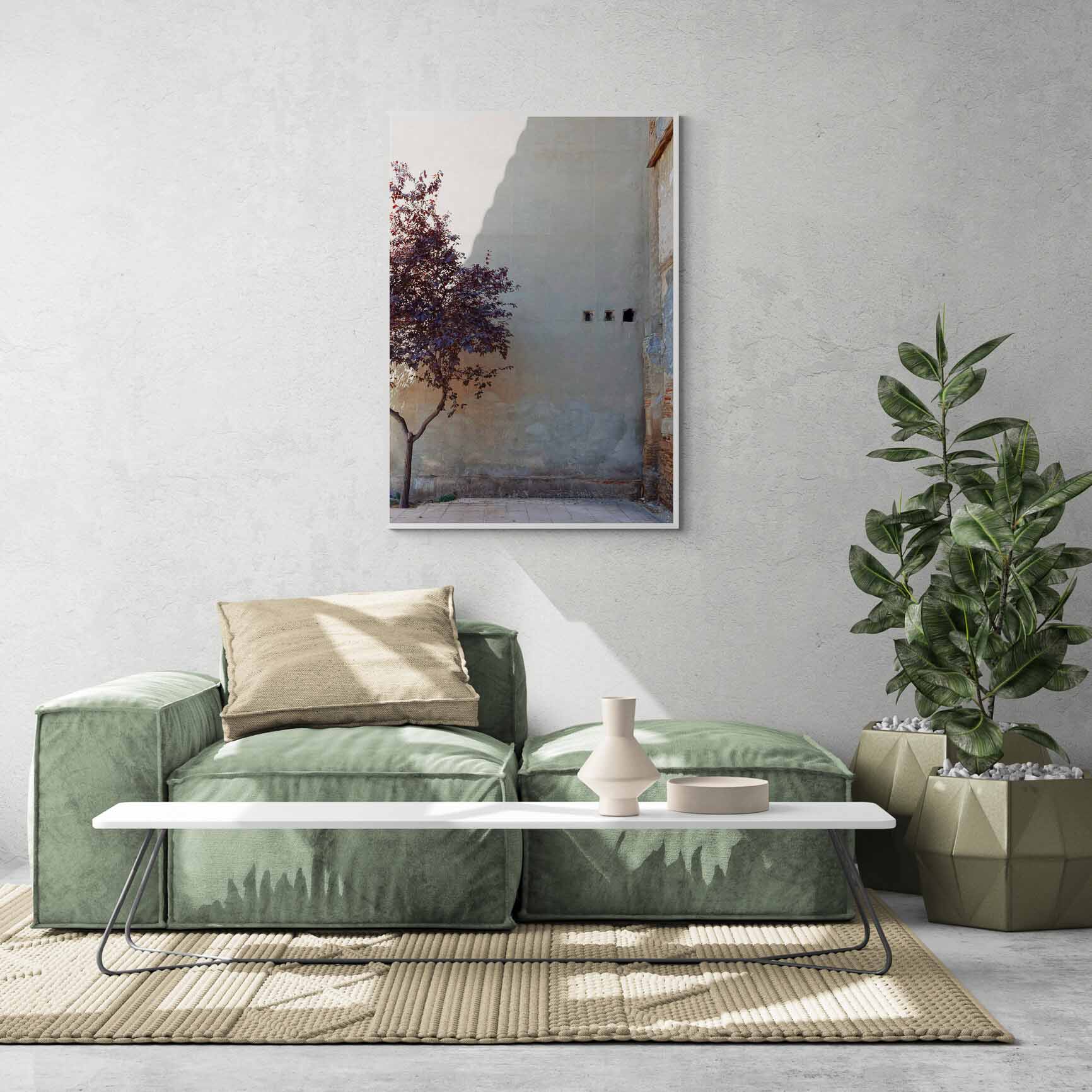 A single tree with autumn-colored leaves beside a large, plain wall with small openings, in Zaragoza, Spain.