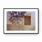 A rustic window with a yellow frame set in an old brick wall, adorned by autumn leaves, in Zaragoza, Spain.