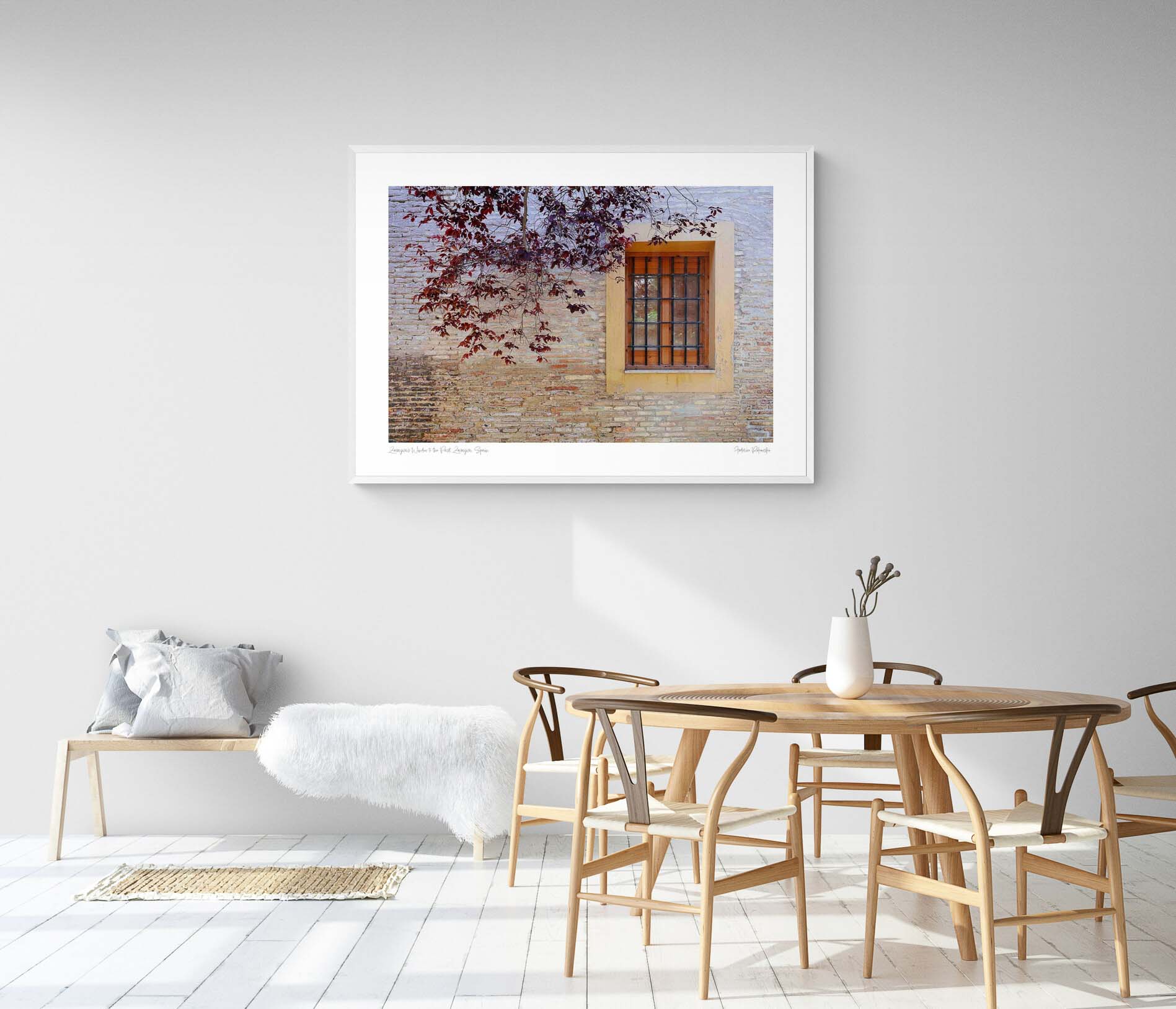 A rustic window with a yellow frame set in an old brick wall, adorned by autumn leaves, in Zaragoza, Spain.